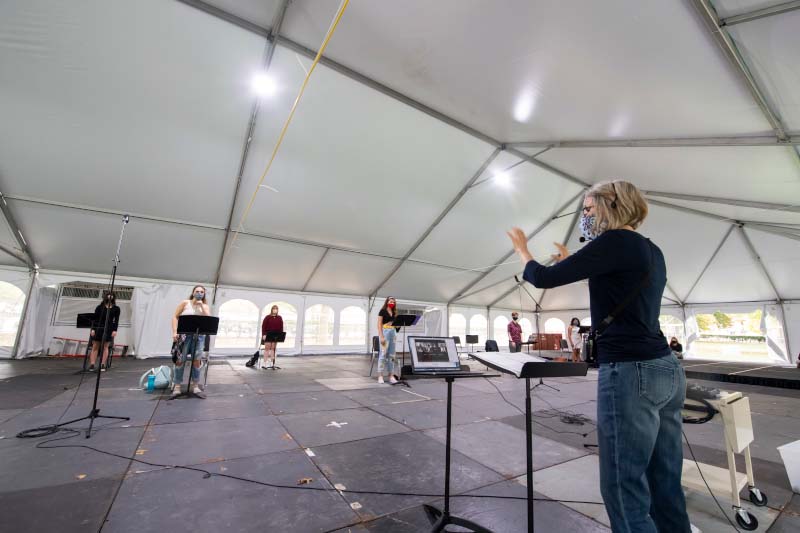 Faculty member in mask teaching students in masks in a large tent.