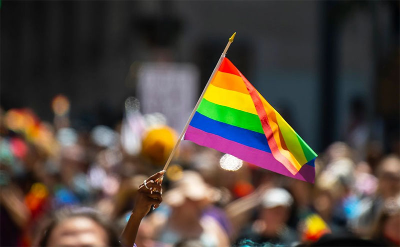 Pride flag being waved in a crowd celebrating LGBTQIA+ pride.