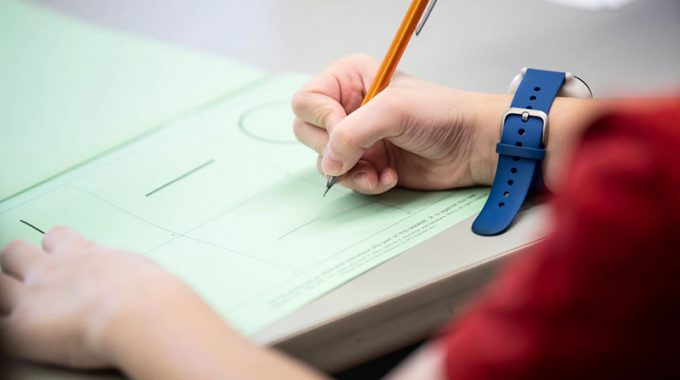 Closeup Of Hand Holding A Pencil Grading/regrading A Paper Exam.
