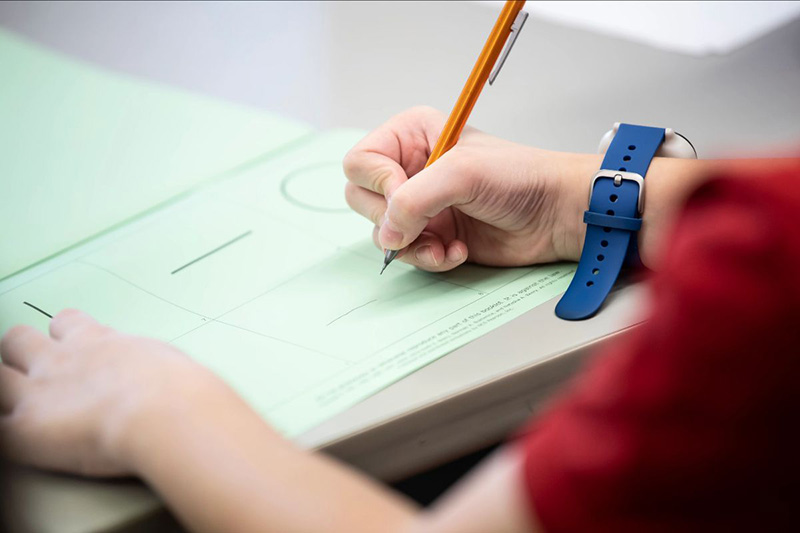 Closeup of hand holding a pencil grading/regrading a paper exam.